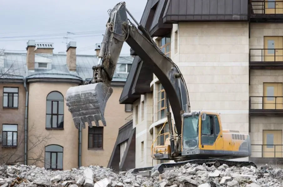 Excavator performing controlled demolition of a commercial building structure.