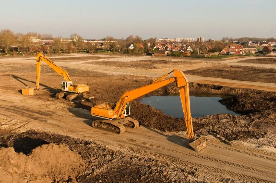 Aerial view of excavators and earthmoving equipment preparing a large construction site.