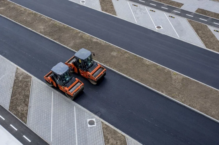 Asphalt paving crew compacting a commercial roadway or parking area.