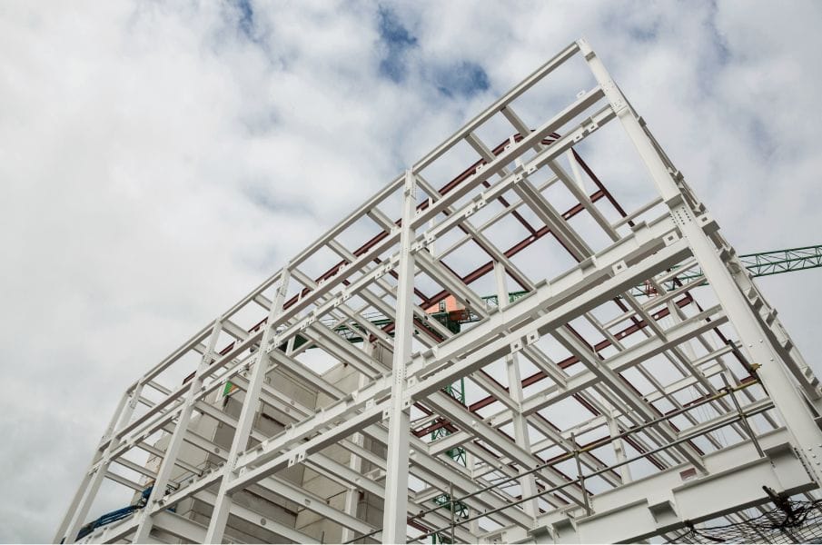 Structural steel frame with beams, columns, joists, and metal decking under construction.