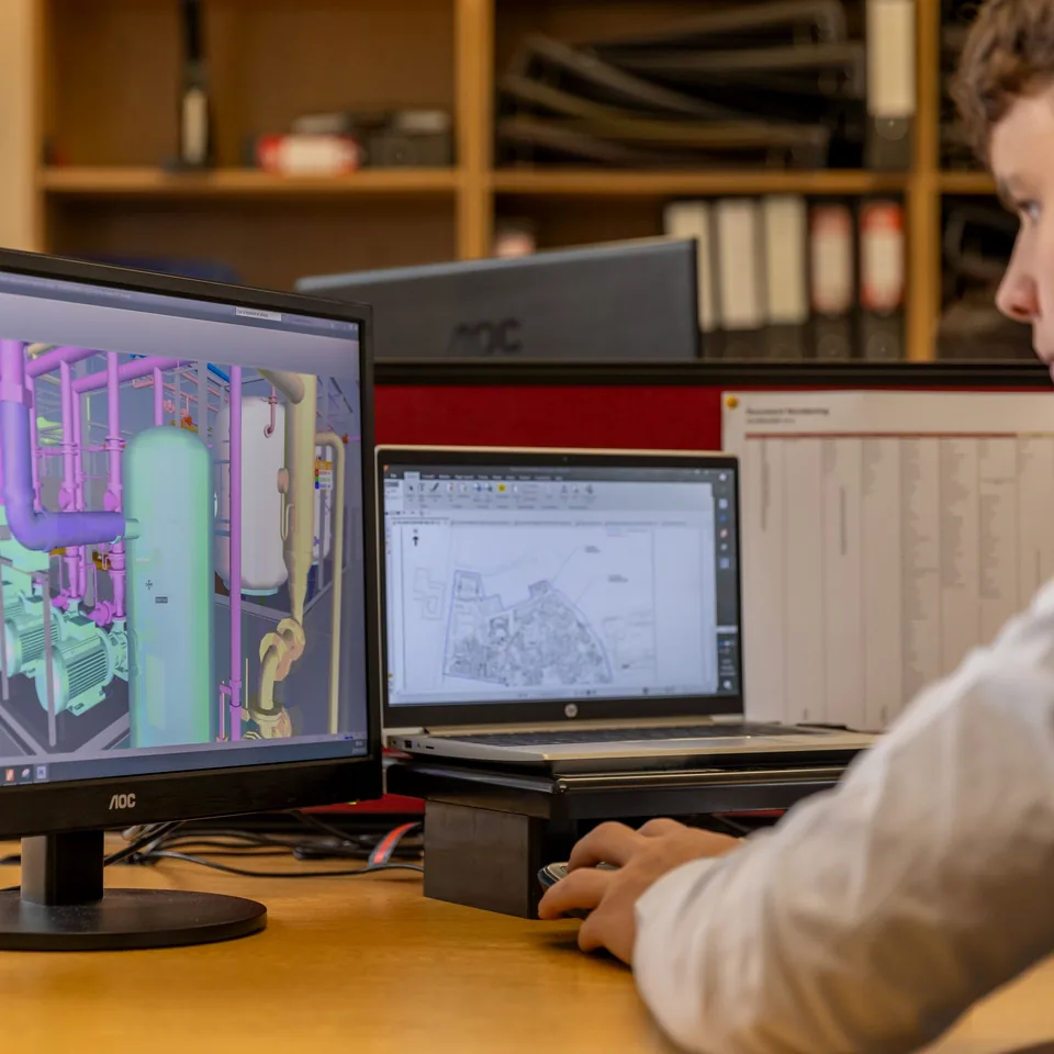 BIM model and construction drawings displayed across estimating workstations