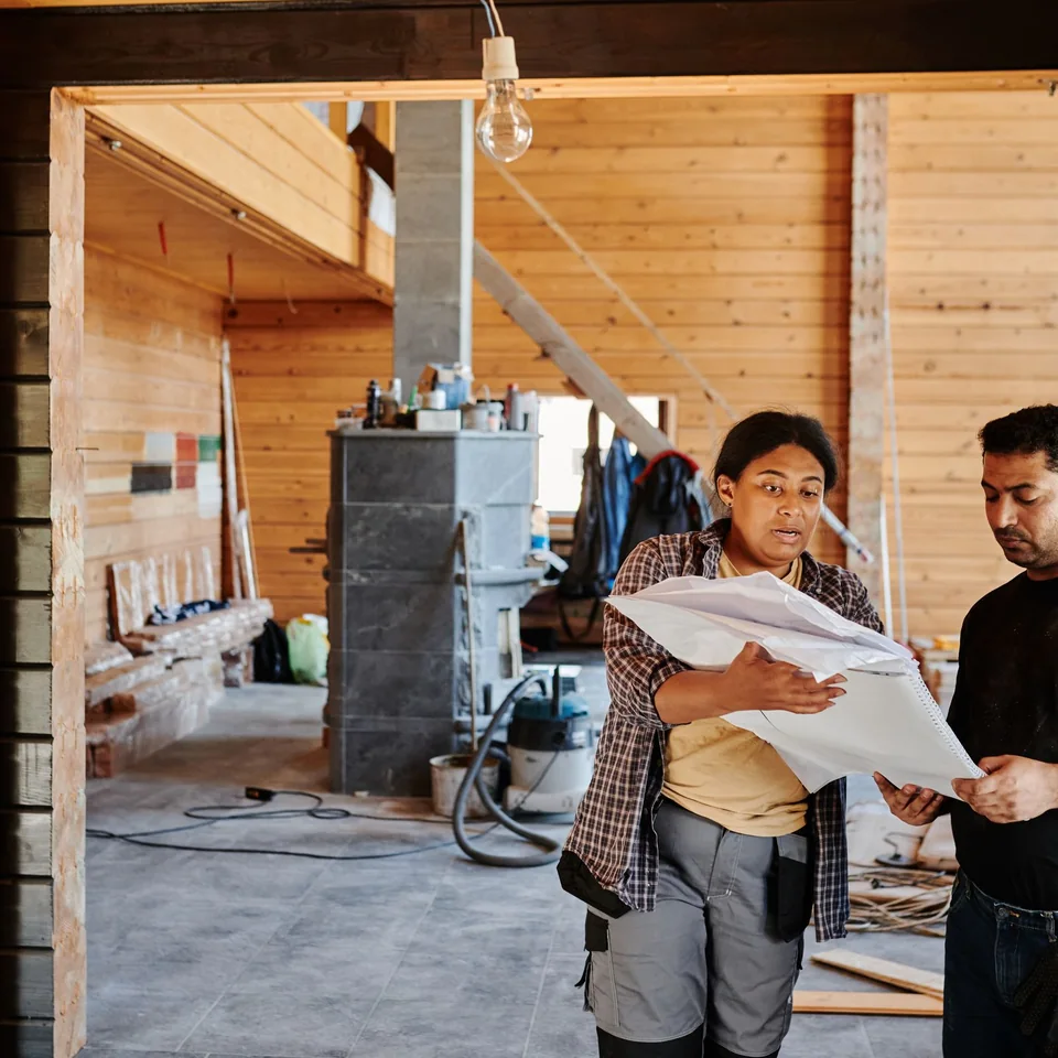 Construction team reviewing revised plans inside an active renovation project