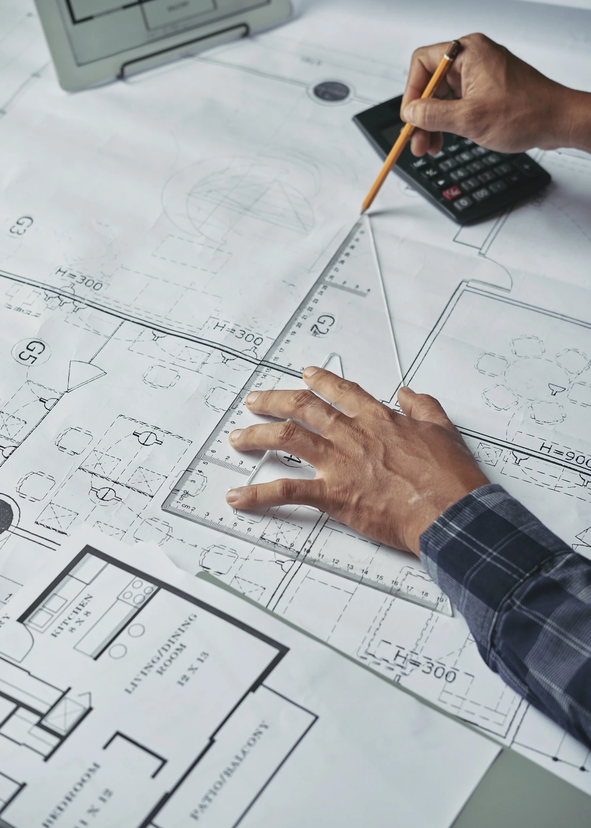 Construction estimator reviewing marked-up drawings, measurements, and project scope documents.