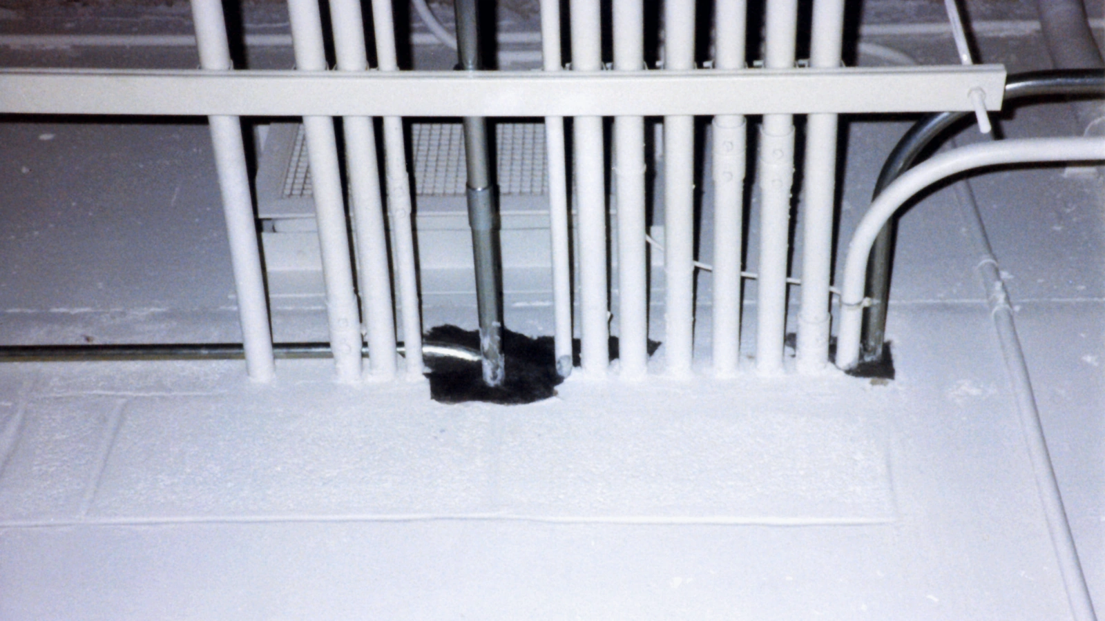 Firestop mortar sealing electrical conduit penetrations through a rated concrete-block wall.