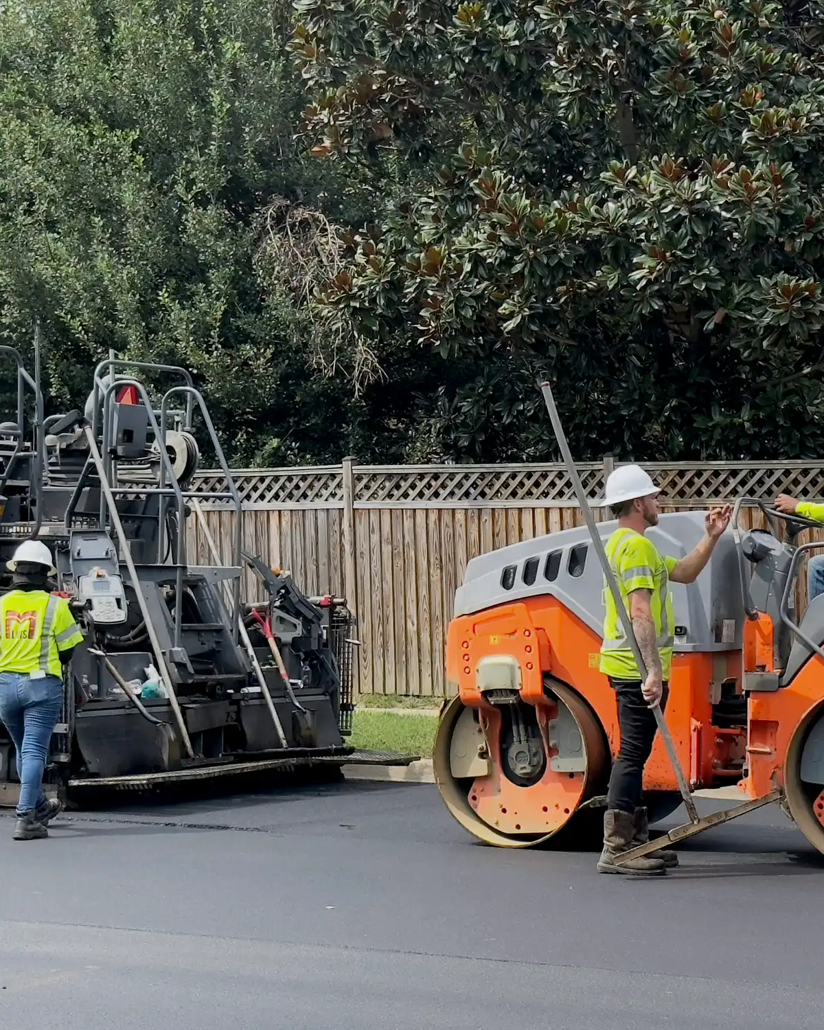 Asphalt paving crew placing and compacting pavement on a commercial site