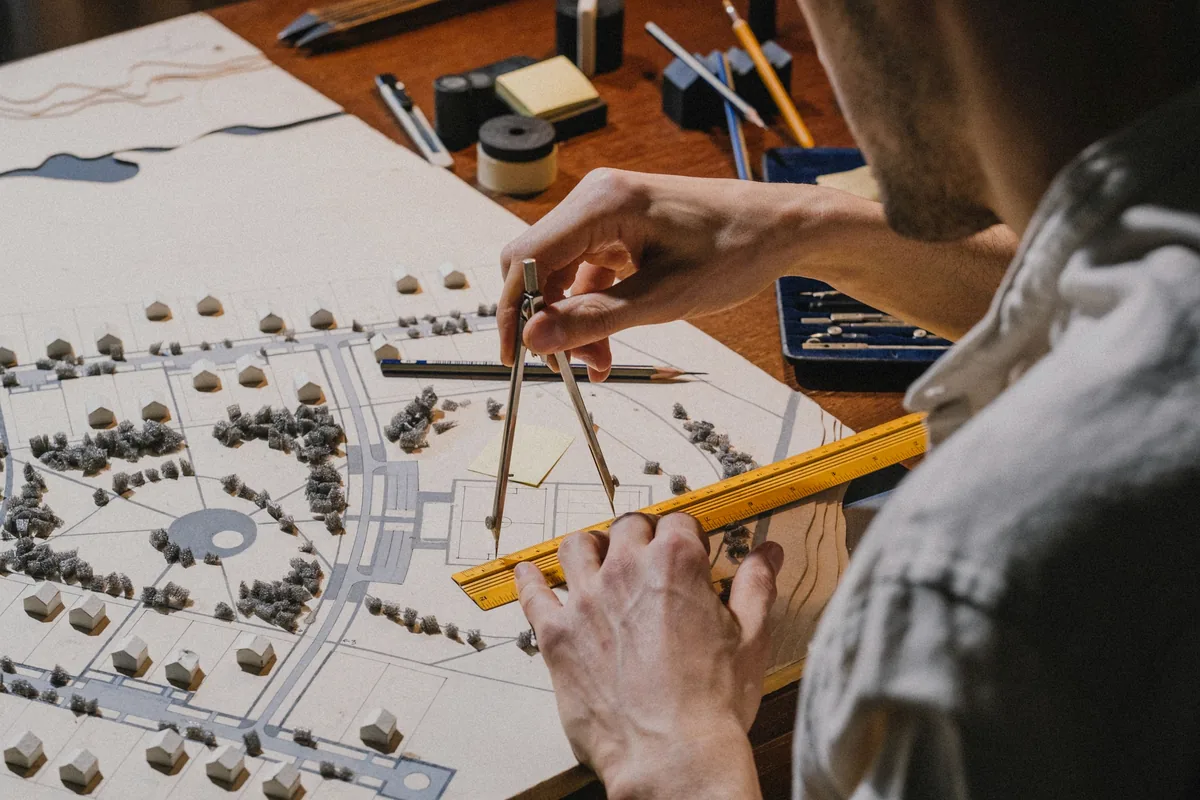 Designer measuring and reviewing a conceptual site plan for early cost planning