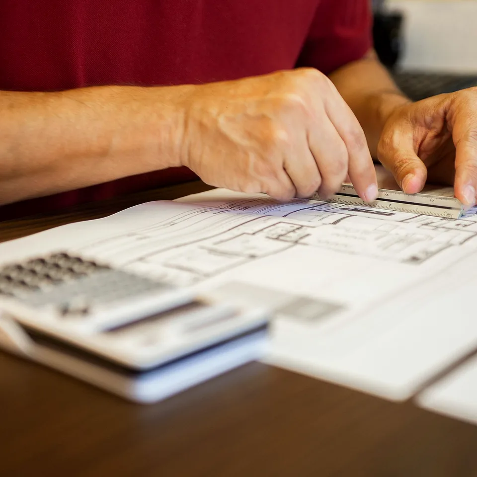 Estimator reviewing construction drawings and quantities with a calculator