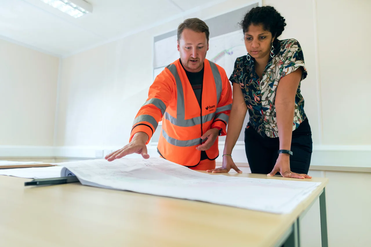 Construction professionals reviewing project plans while comparing estimating deliverables